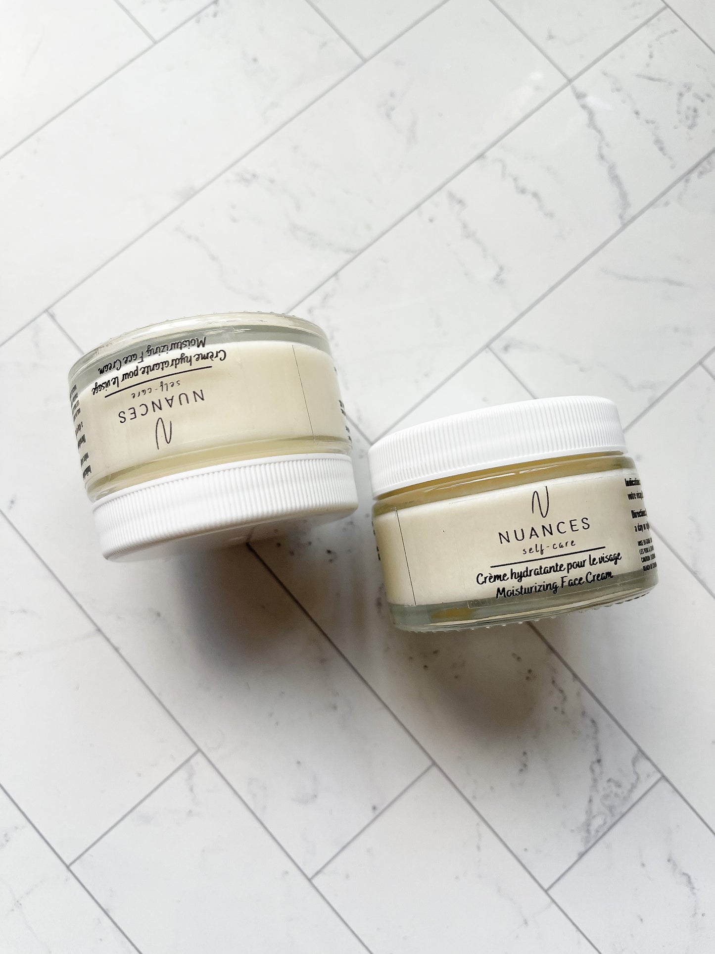An image of two moisturizing face cream on white marble background