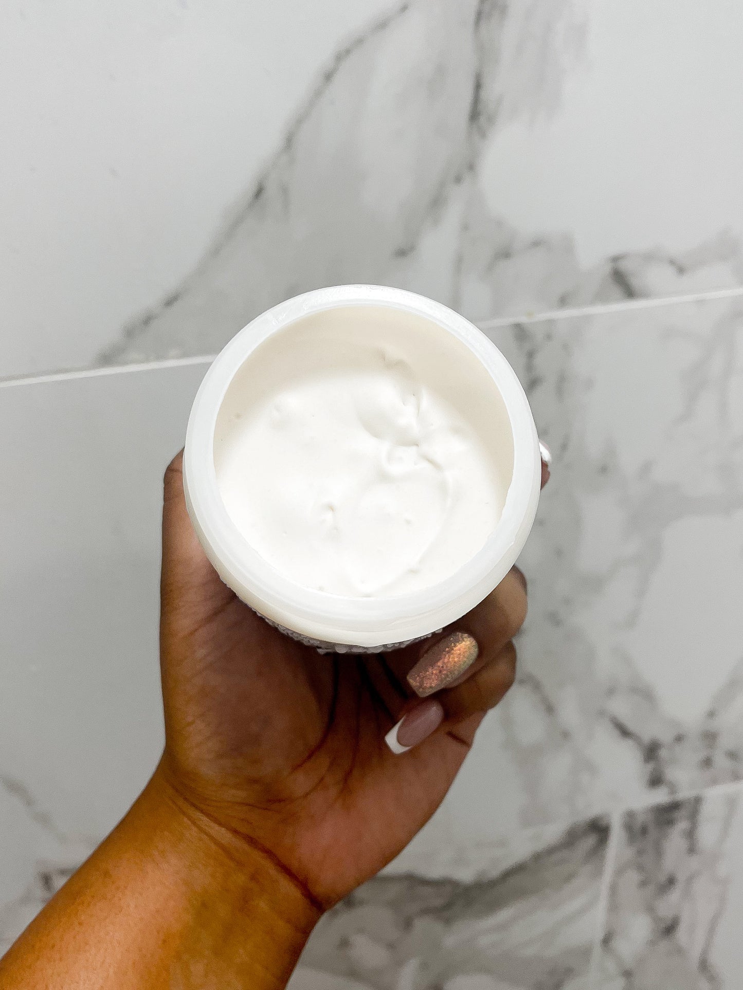 An open jar of the moisturizing hair butter shown in the shower.