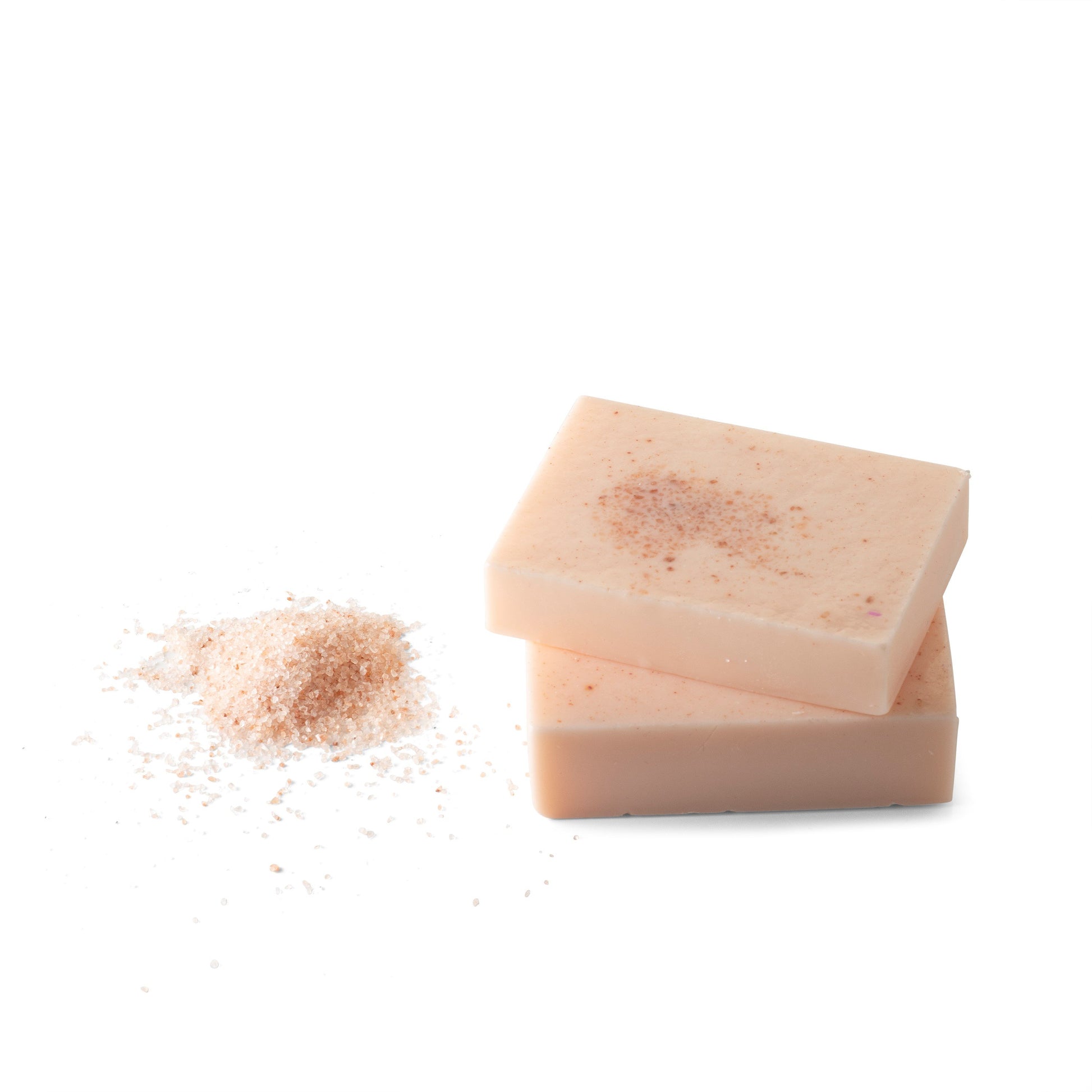 An image of the sea salt body soap next to a handful of sea salt on a white background