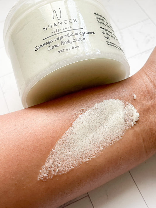 An open jar of the citrus body scrub with an arm showing the product being used